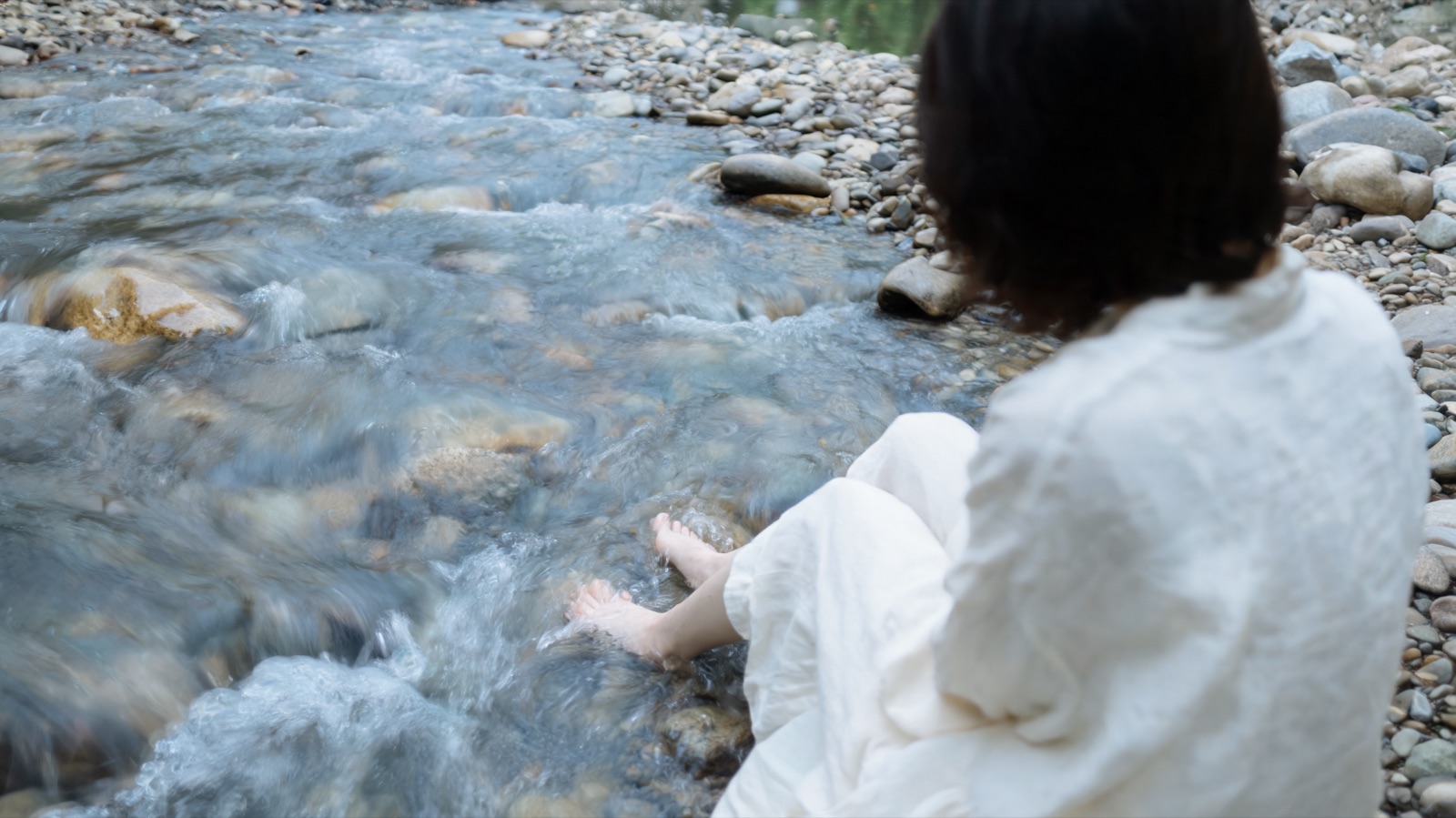 Acqua limpida che scorre su pietre lisce, la corrente mossa dalla lunga esposizione