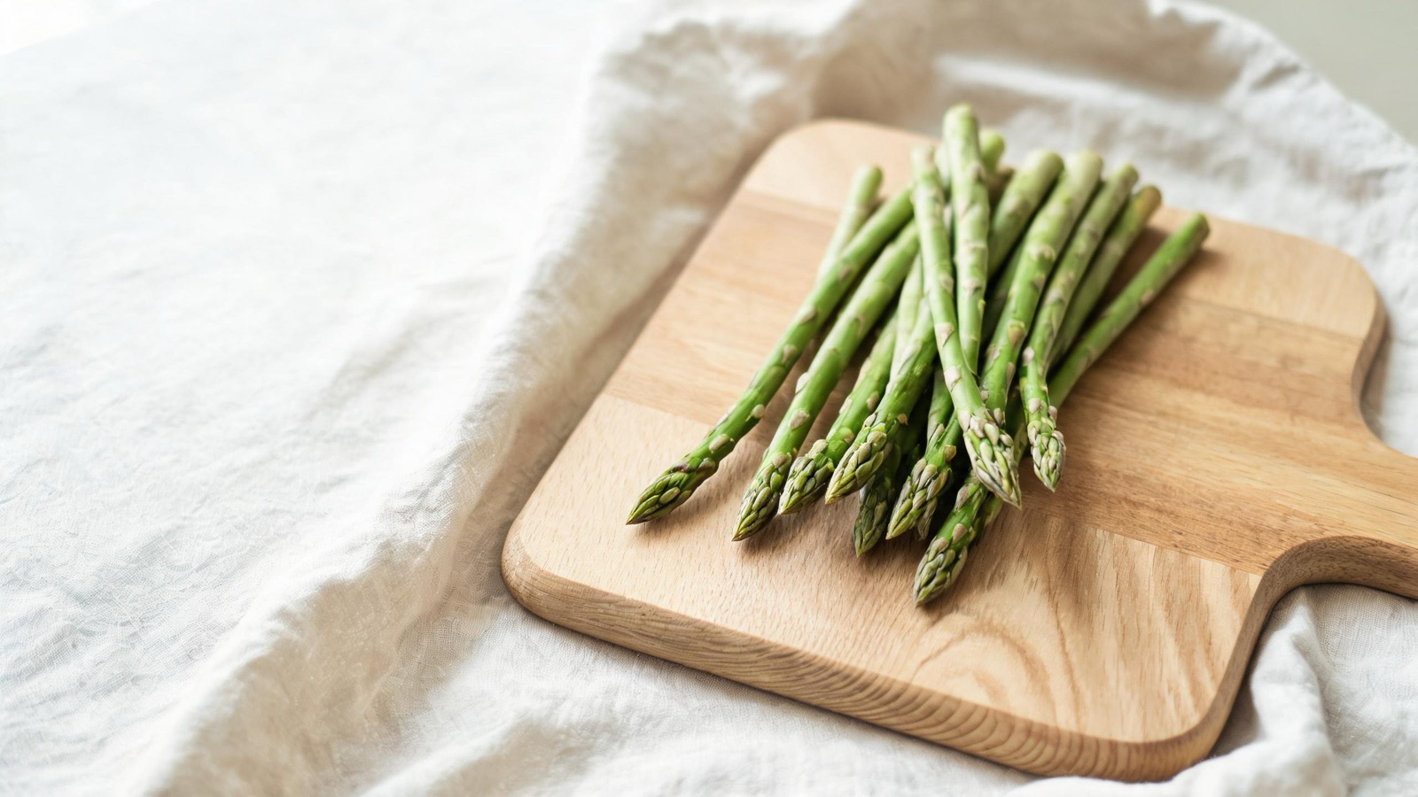 Ingredienti freschi di stagione disposti su un tagliere di legno, luce naturale da finestra