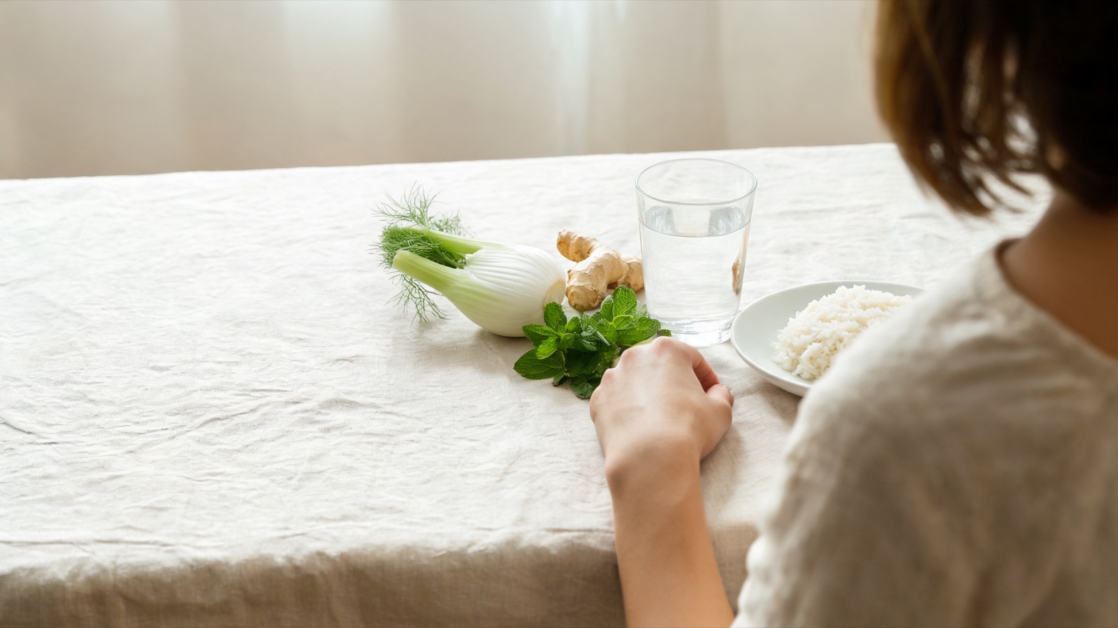 Finocchio, zenzero fresco, menta e un bicchiere d'acqua su lino chiaro